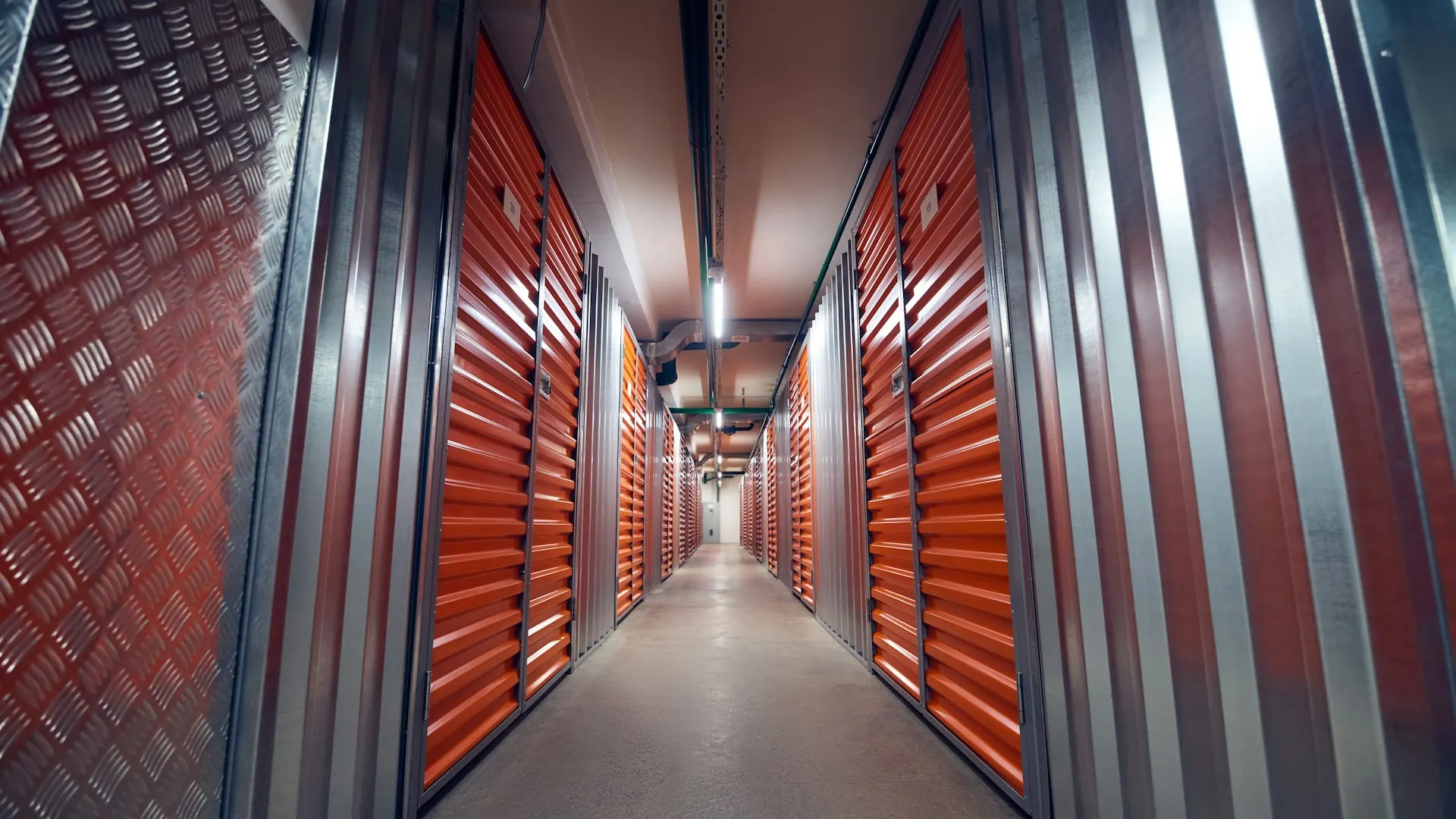Interior corridor of a self-storage facility lined with orange roll-up unit doors